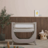 Shnuggle Air Lite Bedside Crib in grey and taupe, featuring a curved design and breathable mesh sides, set in a stylish