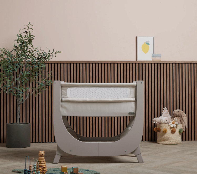 Shnuggle Air Lite Bedside Crib in grey and taupe, featuring a curved design and breathable mesh sides, set in a stylish