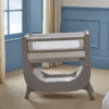 Shnuggle Air Lite Bedside Crib in grey and taupe, featuring a breathable mesh side for easy visibility and airflow.