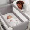 Shnuggle Air Bedside Crib in dove grey with a parent and baby peacefully sleeping side by side.