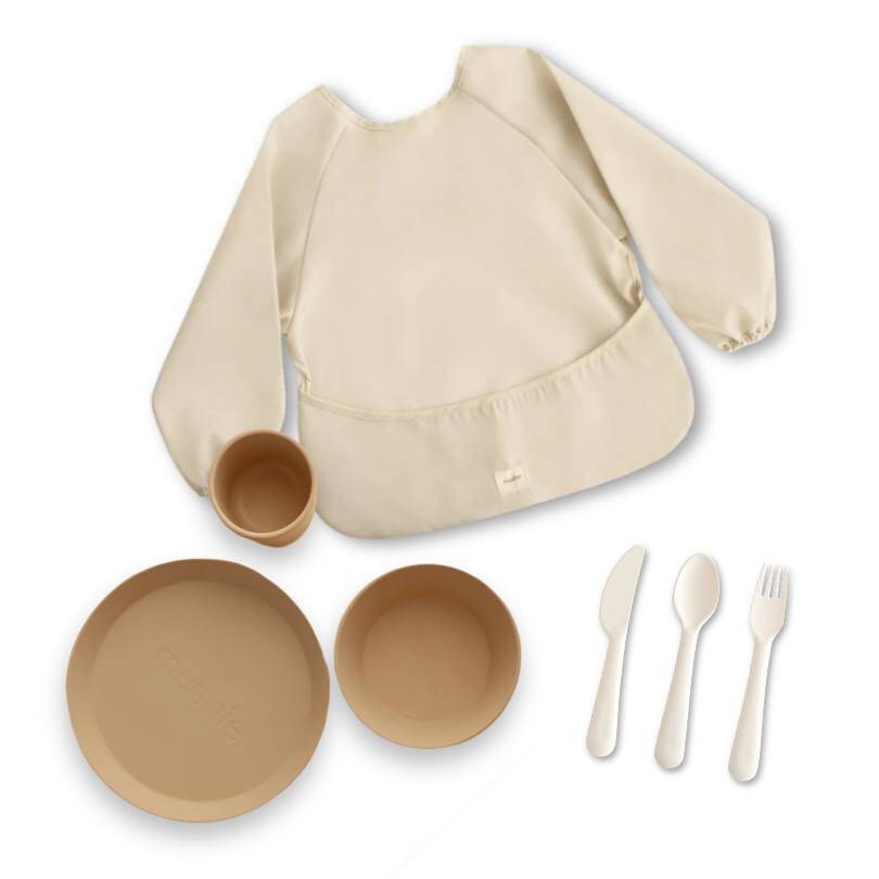 Mushie Stage 3 Feeding Bundle in beige includes a bib, bowl, plate, cup, fork, and knife. Perfect for toddlers.