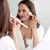 Momcozy Breast Pump S12 Pro discreetly worn while a woman applies makeup in front of a mirror, showcasing a lifestyle