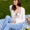 Momcozy Breast Pump S12 Pro worn discreetly under a white sweater, with a woman sitting on a picnic blanket outdoors.