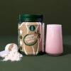 SoFitt™ Advanced Fertility Support powder beside a pink smoothie in a glass, with a scoop and powder on a green background.