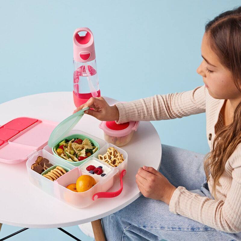 b.box lunch tub in berry smoothie, featuring compartments for snacks and salad, used by a girl at a table.