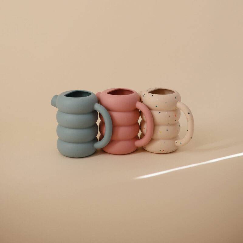 Mushie Silicone Watering Can set in French Blue, Peony, and a speckled design, showcasing a playful, modern aesthetic.