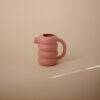 Mushie Silicone Watering Can in Peony, featuring a unique ribbed design and ergonomic handle, set against a soft background.