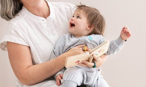 Love To Dream Sleep Suit Long Sleeve 1.0 Tog in white, worn by a baby held by a smiling adult, both enjoying a playful